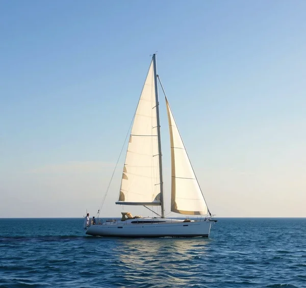 Una barca a vela solitaria naviga su acque cristalline, sotto un cielo terso. La luce dorata e il calore trasmettono armonia senza distrazioni.